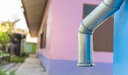 Rain gutter pipe on blue wall blurred background 