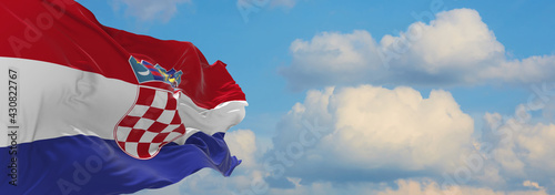 Large flag of Croatia  waving in the wind on flagpole against the sky with clouds on sunny day. 3d illustration