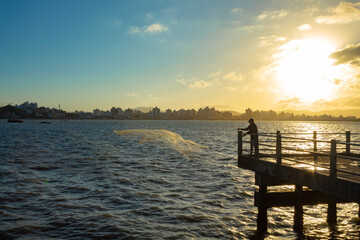 Pôr do sol e na contraluz pescador lançando uma rede no mar Florianopolis, Florianópolis, Santa...