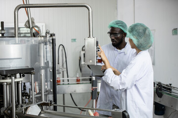 Woman staff worker working train African black man in food factory to operate the machine in clean production room.