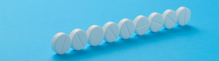 Tablets lined up in row on blue background panoramic banner