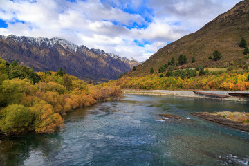 Fototapeta na wymiar Autumn landscape near Queenstown, New Zealand. The Kawarau River, surrounded by willow trees, and the Remarkables mountain range