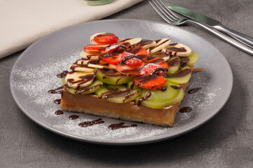 waffle with kiwi banana and strawberries drizzled with chocolate syrup