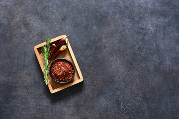 Dry chili peppers in a wooden box on a black background. Spice.