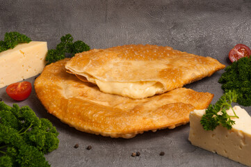 hot appetizer: cheburek with cheese on a gray background