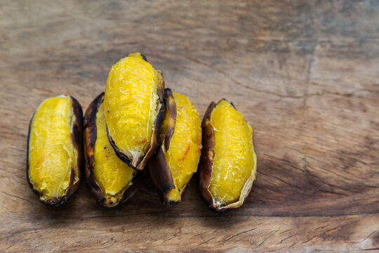 Grilled silver bluggoe banana or Kluai hak mook on old wooden background. Delicious golden brown grilled banana, Ancient food recipes. Copy space, Selective focus.