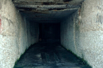 Fototapeta na wymiar A dark deep manmade hole inside a concrete wall. Ominous, disquieting feeling. 