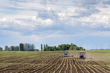 field work in agriculture. farmer's tractor harrows the field after planting seeds. tractor and seeder planting crops on a field.