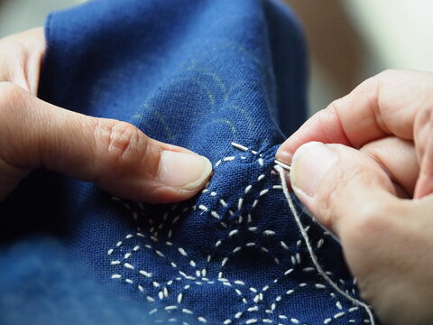 Close up needle in woman's hands sewing running stitch in blue fabric. Traditional Japanese sewing pattern call "SASHIKO".Japanese embroidery, learning ,teaching,how to do, hand craft ,hobby concept.