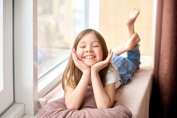 Happy children day. Children Protection Day. smiling girl lies on windowsill on vacation