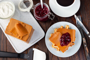 Homemade waffles with norwegian brown cheese and lingon jam, on wooden background, horizontal, top view