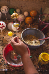 Craftsman painting Christmas spheres in his workshop in different colors, using acrylic paint, diamond paint to give texture and different figures.