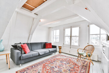 White colored living room with oriental rug furnished with gray sofa and rattan armchair