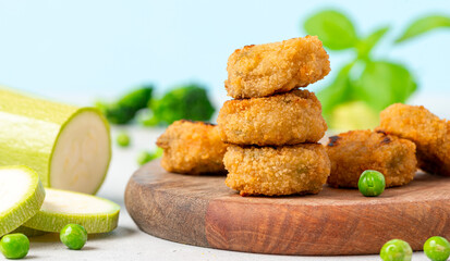 Vegetable nugget. Cooked vegetarian nugget with zucchini, carrots and peas on a wooden board...