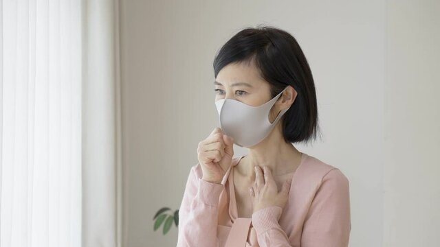 マスクをつけて咳をするシニア女性