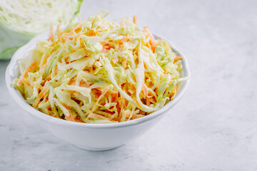 Traditional coleslaw salad with fresh sliced carrots and cabbage in a white bowl