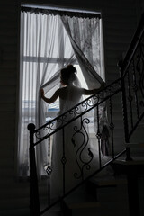 Obraz na płótnie Canvas Silhouette of a happy bride at the window on the wedding day.