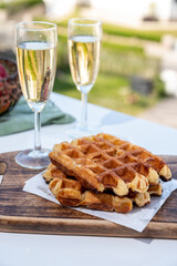 Breakfast with fresh baked belgian waffles and brut champagne sparkling wine in flute glasses served on outdoor bistro terrace in France