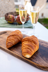 Breakfast with fresh baked croissants and  brut champagne sparkling wine in flute glasses served on outdoor bistro terrace in France