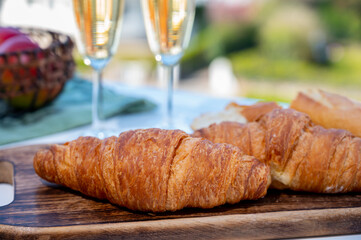 Breakfast with fresh baked croissants and  brut champagne sparkling wine in flute glasses served on outdoor bistro terrace in France