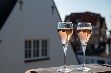 Drinking of rose champagne sparkling wine from flute glasses on outdoor terrace in France