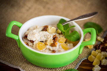 cooked boiled sweet oatmeal with nuts and candied fruits in a bowl