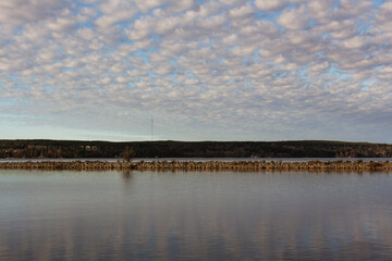 Beautiful landscape with stratocumulus clouds. Peaceful water on the northern lake