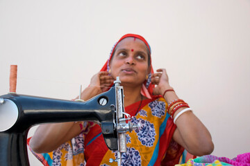 PORTRAIT OF A RURAL WOMAN SEWING CLOTHES	