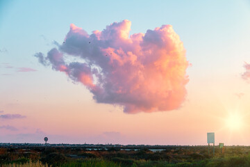 A beautiful cloud of reddish tones in a sunset in the marshes of Chiclana de la Frontera, Cadiz, Spain