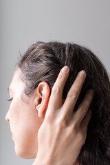 Fototapeta premium 40 year old woman pulling hair back; natural gray hair growing in