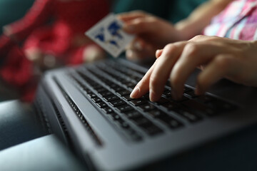 Woman hand holds plastic credit bank card and works on keyboard