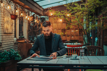Businessman working in a cafe while using laptop and drinking coffee