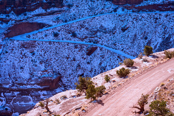 Scenic steep, exposed and snow covered Shafer Trail section of White Rim Road at Shafer Canyon. The winter day at Canyonlands National Park