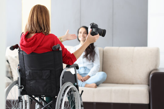 Woman in wheelchair holds camera and takes photo of model