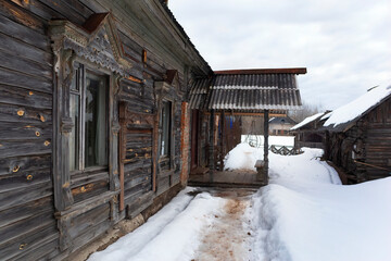 Fototapeta na wymiar Old wooden house with windows and porch in winter.