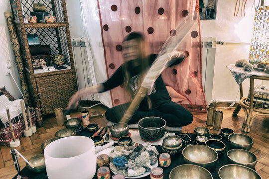 Woman playing with a Tibetan Singing Bowls, Himalayan bowls. Tibetan Singing Bowls Treatment. Tibetan sound massage. Photography with the motion with woman.