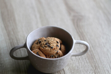 Bowl of chocolate chip cookies on wooden table. Selective focus.