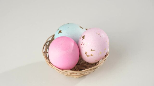 Painted Easter eggs in a basket spinning on a white background