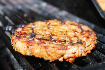 Close-up of a hamburger patty cooking on a barbecue grill.