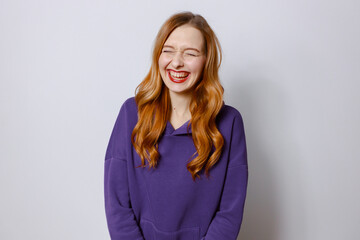 redhead women laughing in purple hoodies. Light background