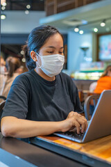 Vertical portrait of woman wearing protective mask and using laptop