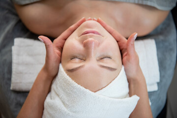 women lie on the beuty procedure for face lie with towel on head smile
