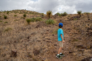 boy looking up mountain trail in desert