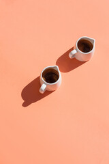 glass of pure water and cup of black espresso coffee on pink background. top view, copy space, flat lay. trendy food style photo with sunlight and deep shadow