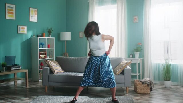 Young beautiful woman in green skirt and white top, talented dancer is practicing at home, making efforts to improve her skills, getting ready to performance, Slow motion.