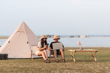 Fototapeta premium Men and women on vacations and camping trips He is using a computer to check the internet.