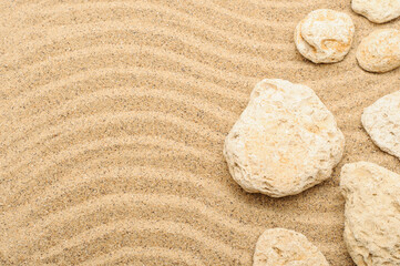 Fototapeta na wymiar Waves of beige sea sand with stones, texture, sand background, summer concept