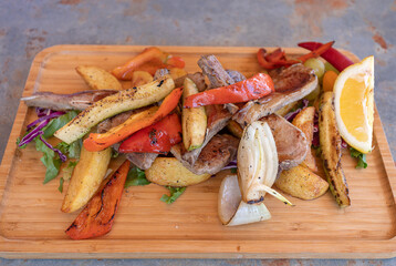 Lamb ribs with vegetables on a wooden plate.