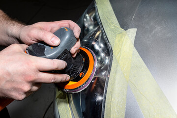 A car sprayer polishes the headlamp with a pneumatic sponge grinder.