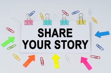 On the table there are paper clips and directional arrows, a sign that says - Share Your Story